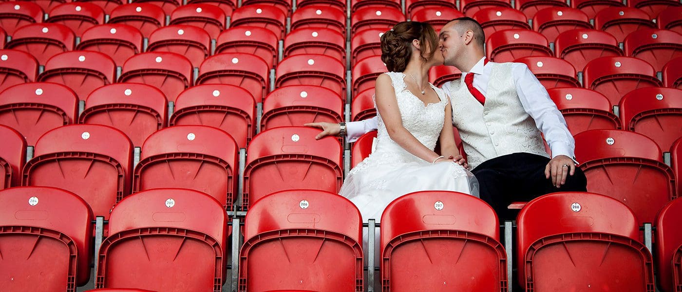Newly married couple kissing whilst sat in the Totally Wicked Stadium seats
