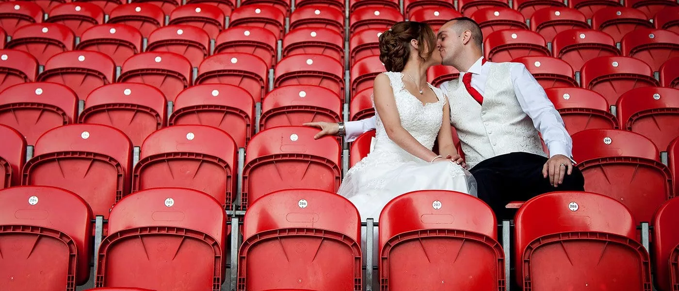 Newly married couple kissing whilst sat in the Totally Wicked Stadium seats