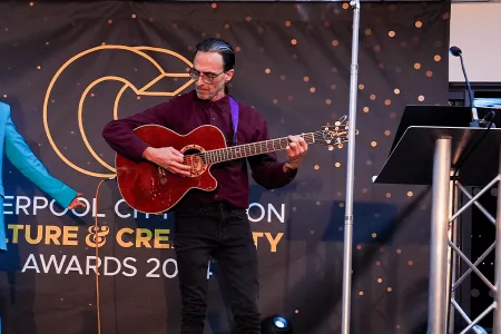 woman in blue suit and man with guitar on stage