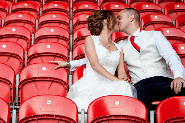 bride and groom kissing on red chairs
