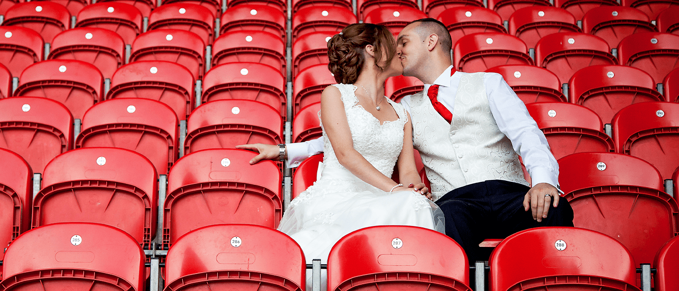 bride and groom kissing on red chairs
