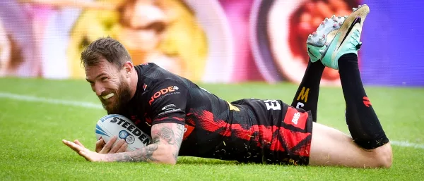 A rugby player, a man, is lying on the ground with his hands resting on his knees, showing signs of exhaustion.