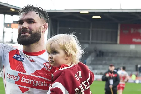 rugby player holding child on pitch