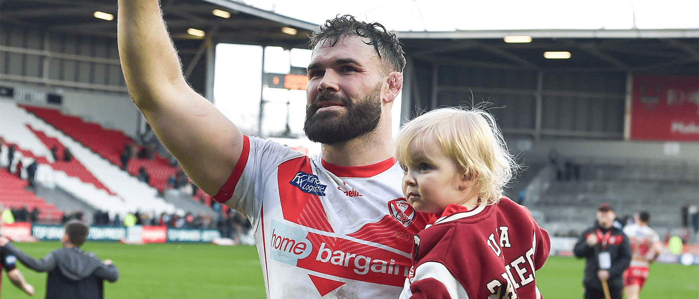 rugby player holding child on pitch