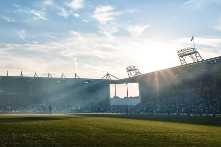 rugby match with sun peering over stands