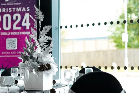 white festive decorations on table with crackers and wine glasses